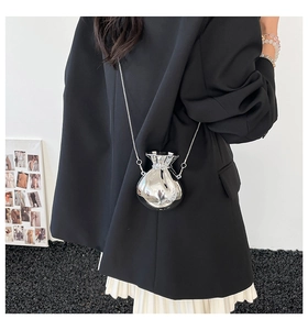Detail of silver mirror finish mini money bag with slim metal chain strap on model