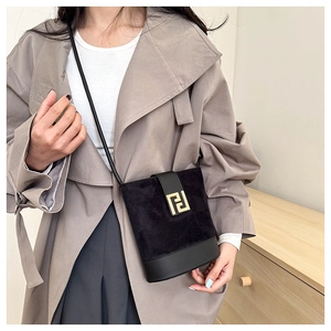 Close-up of black bucket bag with gold geometric buckle on a grey trench coat