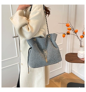 Detail of silver glitter tote bag with golden letter pendant and chain strap
