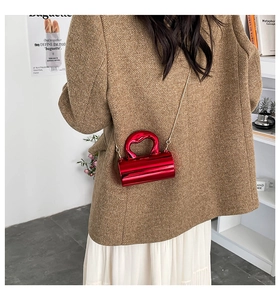 Rote zylindrische Tasche mit Herzgriff auf Modellrücken mit goldener Kette präsentiert