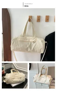 Detail of a large cream travel duffel bag with reinforced handles and removable shoulder strap
