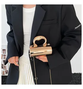 Detailansicht der goldfarbenen Zylindertasche mit unregelmäßigem Griff und Kette
