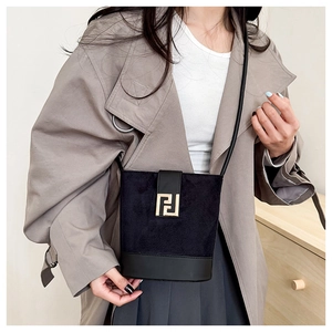 Detail of black patchwork bucket bag with suede texture and golden metal buckle