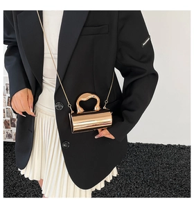 Detailaufnahme einer goldenen zylindrischen Mini-Tasche mit Metall-Finish und Kette