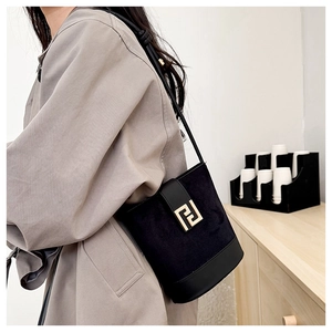 Detail of black suede and smooth leather bucket bag with gold clasp shown on model