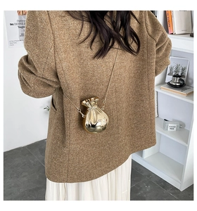 Close-up of a stylish gold money bag-shaped metal crossbody bag with a sleek chain strap