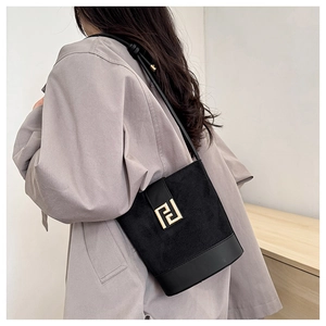 Detail of black suede bucket bag featuring a prominent gold geometric metal buckle closure