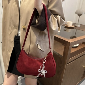 Sac bandoulière bordeaux en daim mat avec breloque cœur perlé porté par mannequin