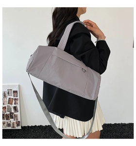 Minimalist grey waterproof nylon travel bag shown on shoulder for sizing and fit