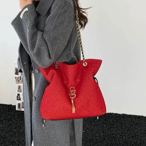 Sac seau rouge tendance avec bandoulière chaîne dorée, pompon et fini texturé
