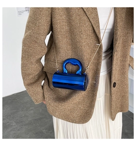 Close-up of a mini cylindrical handbag in electric blue with gold chain on model