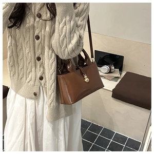 Dettaglio della borsa in pelle marrone scuro con chiusura dorata e tracolla regolabile