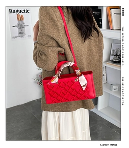 Detail of red luxury handbag featuring 3D embossed patterns and silk scarf handle