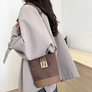 Elegant brown suede and leather bucket bag with gold metal buckle shown from a side view