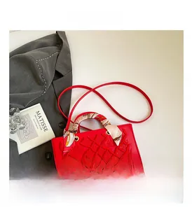 Close-up of red embossed handbag with silk scarf wrapped handle on white background