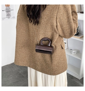 Detail of a deep coffee cylinder bag with metallic finish and gold chain strap