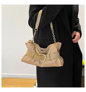 Dettaglio borsa hobo beige a pieghe con catena dorata e fibbia decorativa sulla tracolla