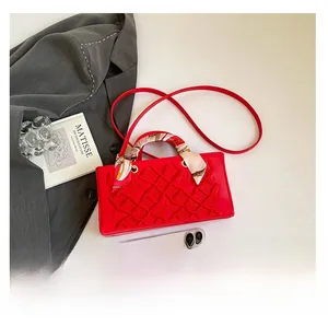 Detail of red luxury square bag with geometric texture, silk scarf and size comparison