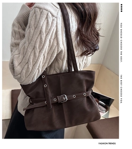 Detail of dark brown shoulder bag with metal eyelets and buckle on model shoulder