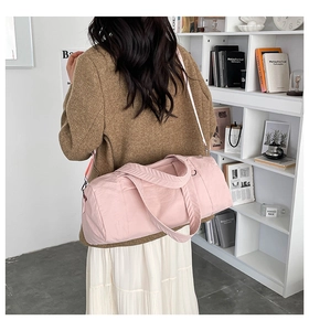 Rear view of a model carrying a soft pink nylon duffel bag in a bright, modern interior