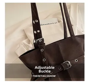 Detail of dark brown faux suede tote with silver grommets and adjustable metal buckle