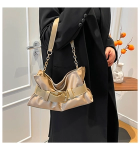 Dettaglio della borsa a pieghe beige con catena in metallo dorato e fibbia decorativa