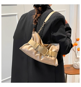 Dettaglio della borsa tote beige con fibbia e tracolla in pelle e catena dorata