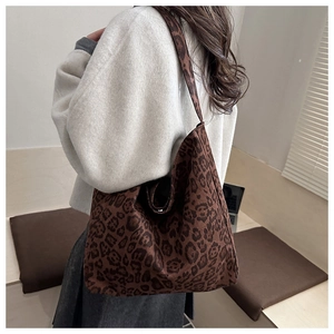 Detailed side view of leopard print tote bag with wide straps on a minimalist background