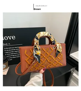 Detail of luxury brown handbag with embroidery, silk scarf handle, and adjustable strap