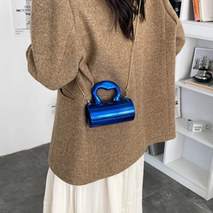 Moderne elektric blauwe metallische Zylindertasche mit Goldkette am Modell gezeigt