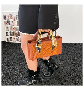 Close-up of brown embroidered quilted handbag with silk scarf handle detail