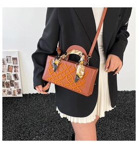 Detail of brown faux leather handbag with woven texture and a decorative floral scarf