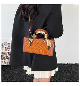 Brown leather handbag with embroidery and scarf detail shown on person for fashion styling