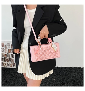 Detailed embroidery on pink crossbody bag with scarf-wrapped handle and floral embossing