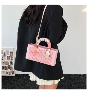 Pink embossed handbag with floral silk scarf handle, worn by model in elegant outfit