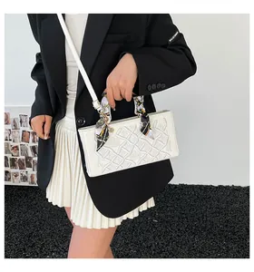 Detail of white quilted handbag featuring textured woven patterns and decorative silk scarf