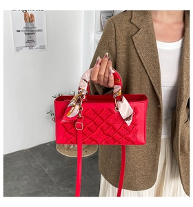 Close-up of red quilted leather handbag featuring a silk scarf handle and crown embossing