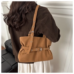 Detail of tan shoulder bag featuring silver metal eyelets and decorative belt strap
