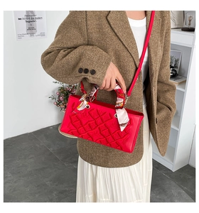 Detailed shot of red crossbody bag with geometric texture and silk scarf decoration