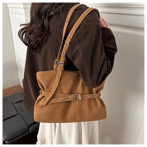 Detailed view of brown leather tote bag with metal buckles and vintage strap details
