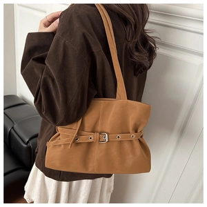 Brown tote bag with decorative strap and buckle shown on shoulder for daily commute