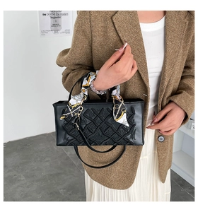 Detail of black embroidered quilted handbag with printed silk scarf wrapped around handle