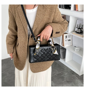 Close-up of black embossed handbag featuring elegant geometric texture and a decorative scarf