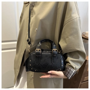 Close-up of black retro Boston bag with gold rivets and adjustable leather strap