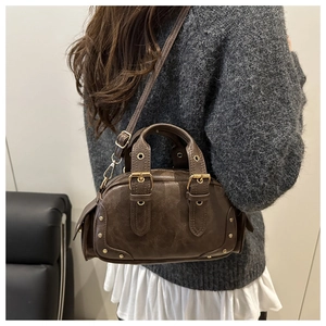Detail of vintage brown leather boston bag with metal rivets worn as a crossbody purse
