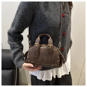 Detail of vintage brown mini bowling bag with metallic studs and side buckle straps