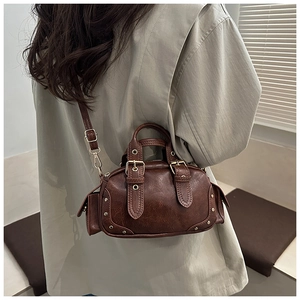 Detailed view of vintage brown pebbled leather bowling bag with rivet accents and buckles