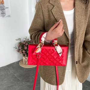 Red quilted handbag with heavy embroidery, crown patterns, and floral scarf handle detail