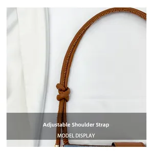 Detail of adjustable brown leather knotted strap on a blue denim shoulder bucket bag