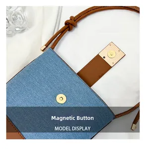 Close-up of the gold magnetic closure on a denim and brown leather bucket bag
